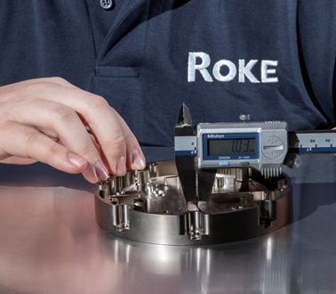 A Roke engineer works on a piece of technology. He is wearing a blue Roke polo shirt.