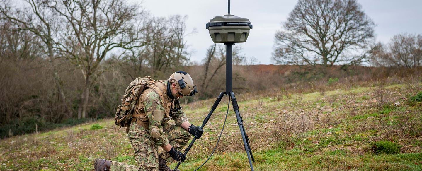 A soldier works on a PERCEIVE system in a field