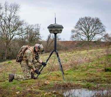 A soldier works on a PERCEIVE system in a field
